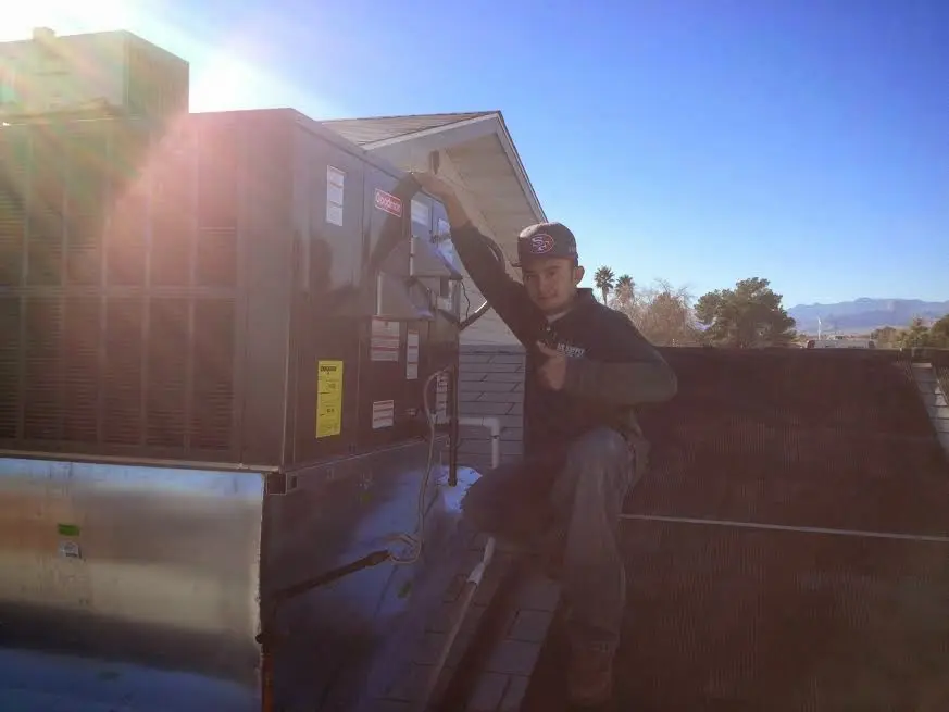 HVAC technician performing Air Duct Cleaning on a rooftop unit in Elburn